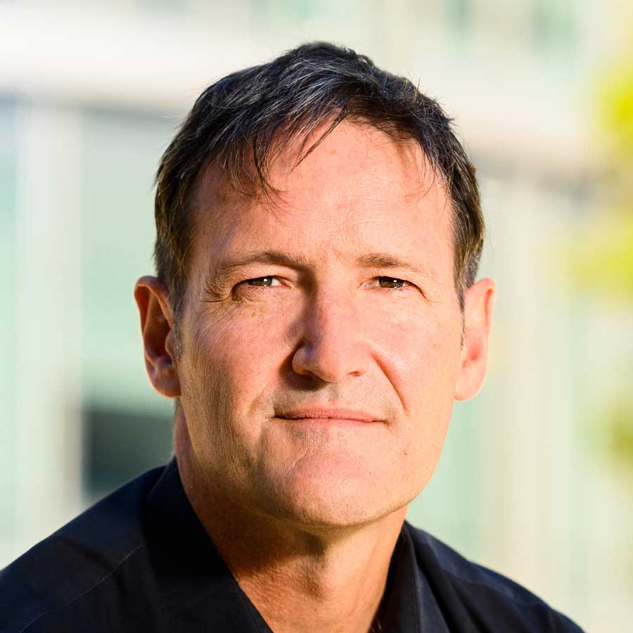 Man with dark hair looks at camera