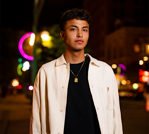 portrait of a young man on a street at night with neon lights in the background