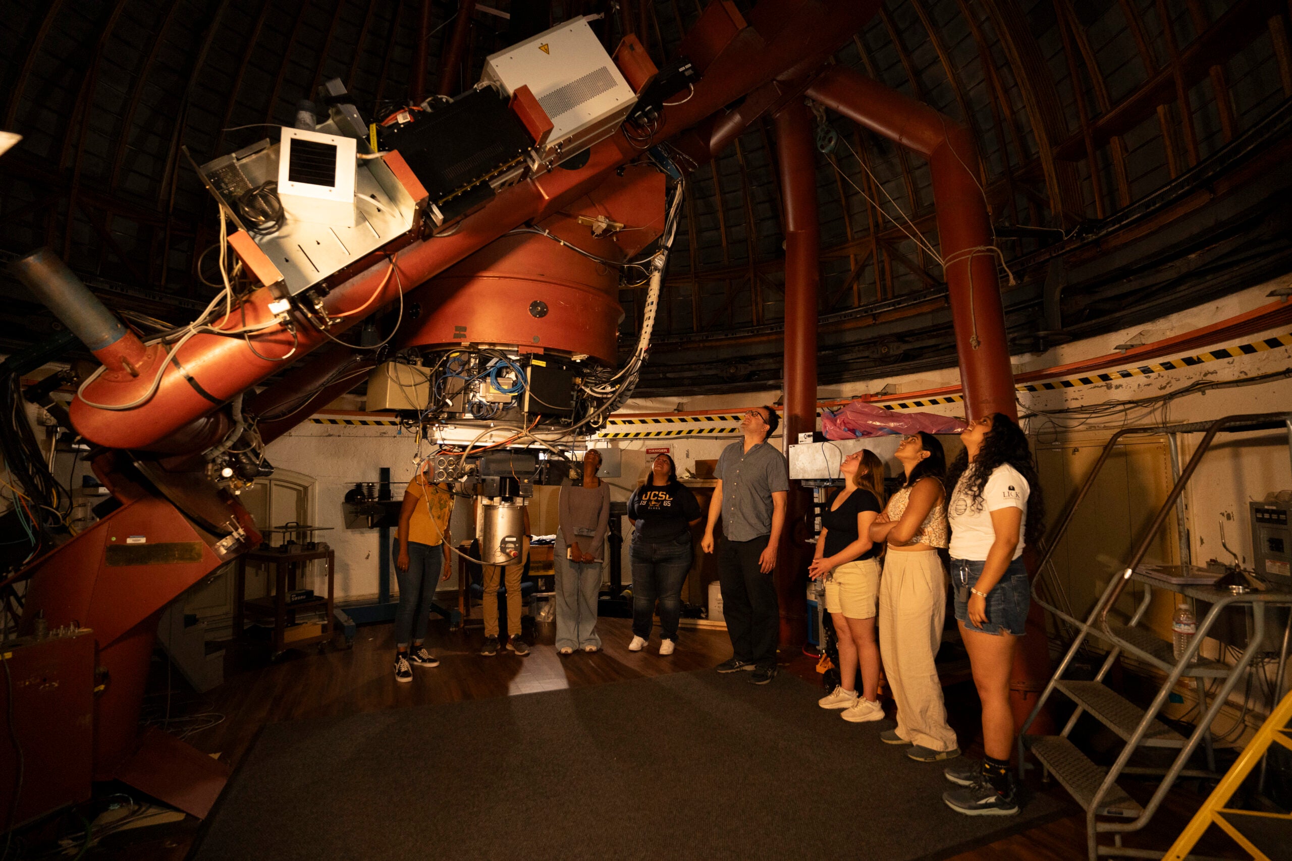 About 10 students look up at a telescope dome