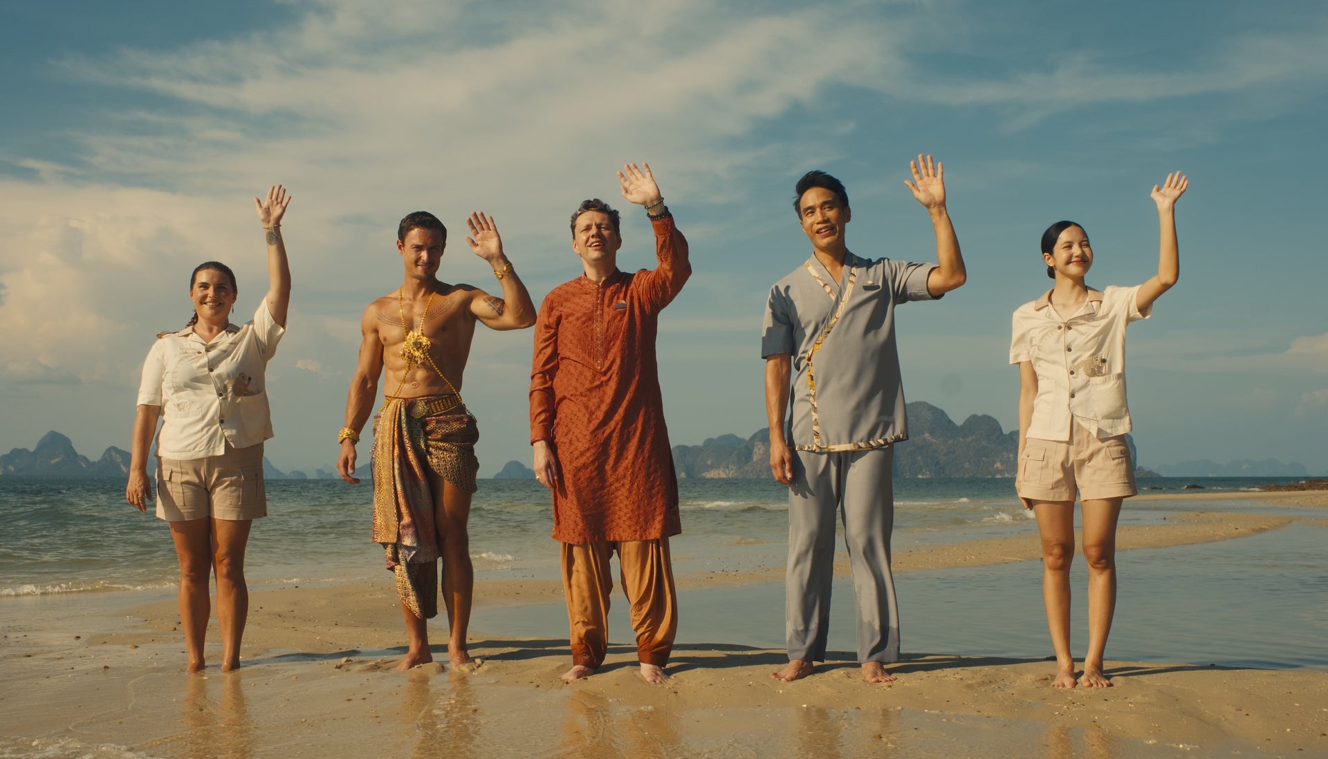 Five staffers at The White Lotus wave on a beach to new arrivals