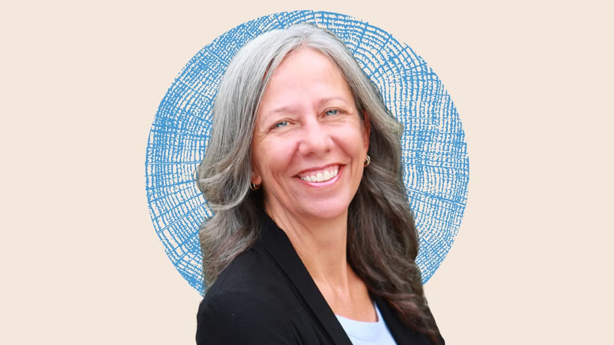 Woman with shoulder-length wavy gray hair smiling in a black jacket on an illustrated backdrop with a blue textured circle behind her
