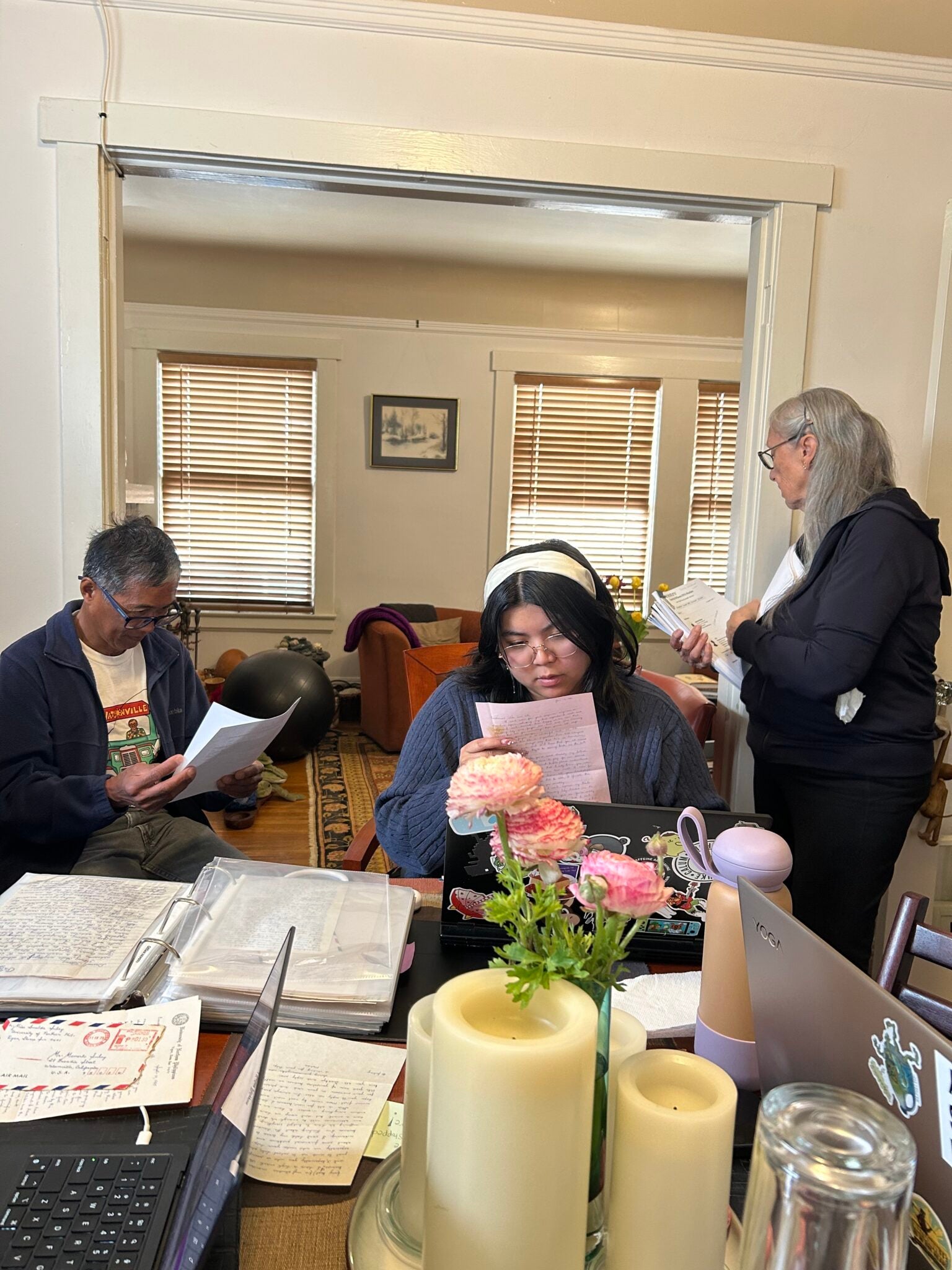 In the interior of a home, three people leaf through papers