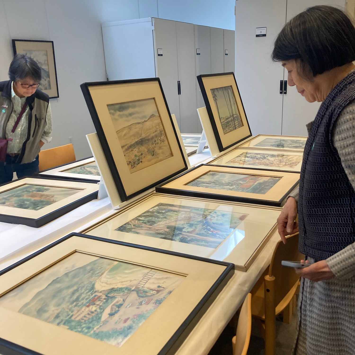 Two women looking at framed artiworks on a counter