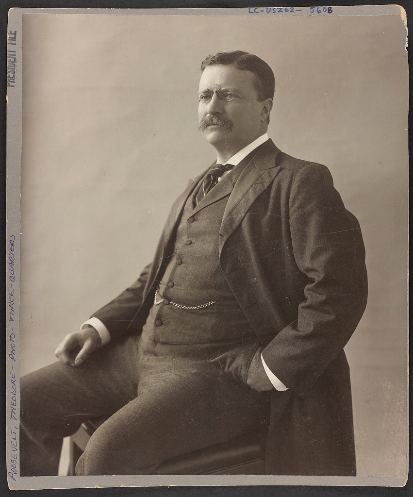 A black and white portrait of President Teddy Roosevelt, seated
