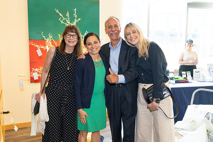 Four people pose for a photo, with a mustached man in the middle giving a thumbs up