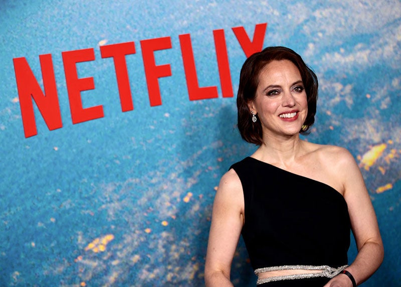 Amy Mainzer, in black tie attire, smiles for a red carpet photograph