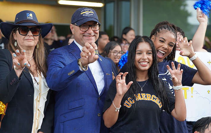 Chancellor Muñoz and students pose for the camera making bobcat claws