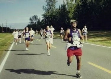 Mel Man smiles broadly while running a road race
