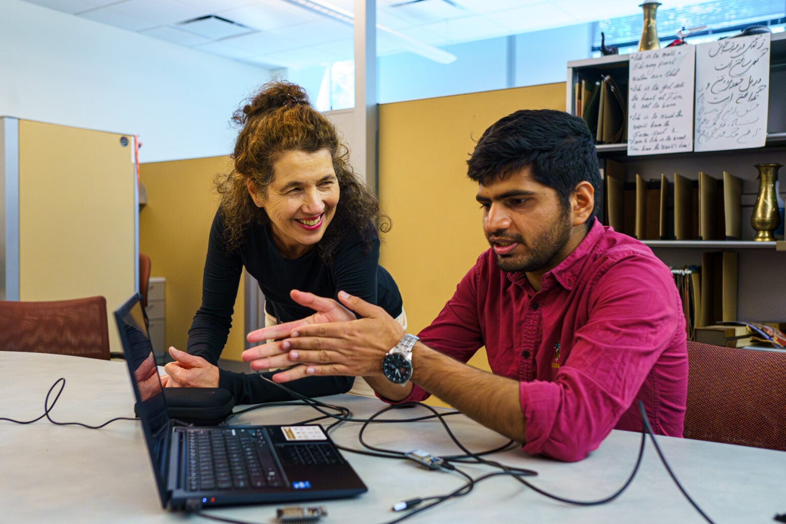 Katia Obraczka and Nayan Bhatia with a computer in the lab.