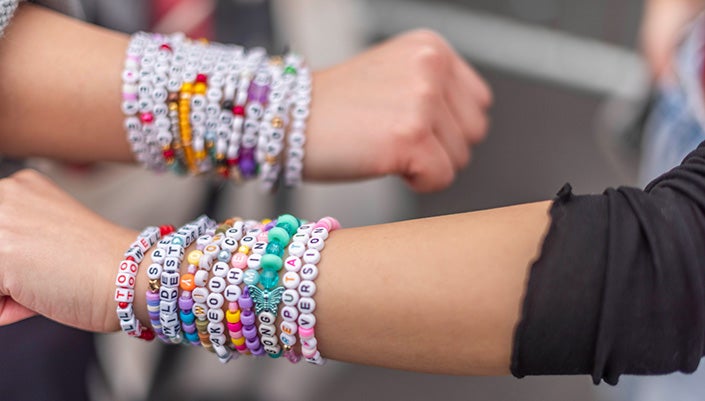 Two arms with Eras Tour friendship bracelets stacked on wrists