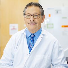 Don Kohn smiles for a portrait wearing a white coat in an exam room