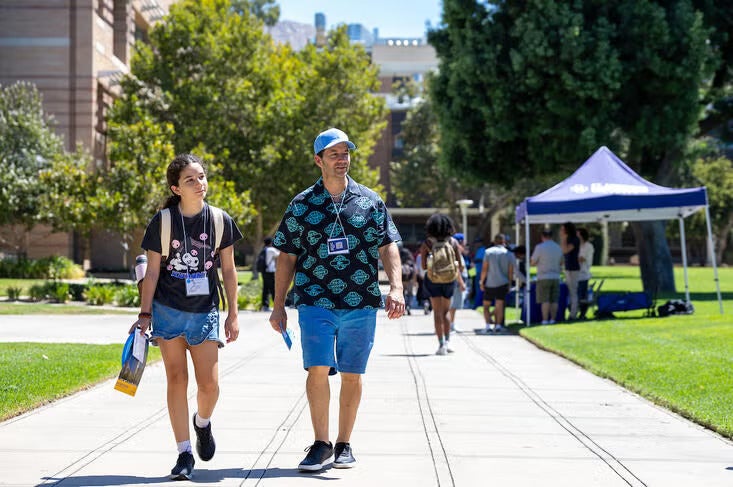 A girl walks with her dad on the UC Riverside campus on a sunny day