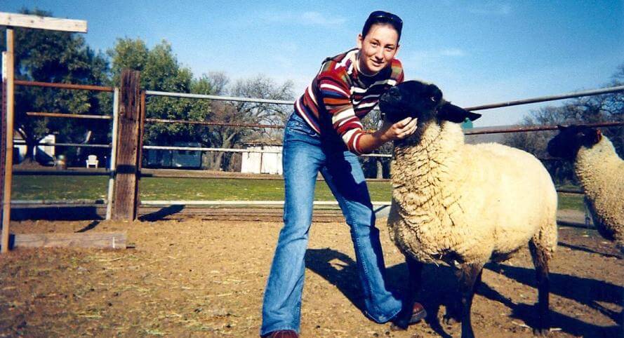A young woman next to a sheep in a paddock