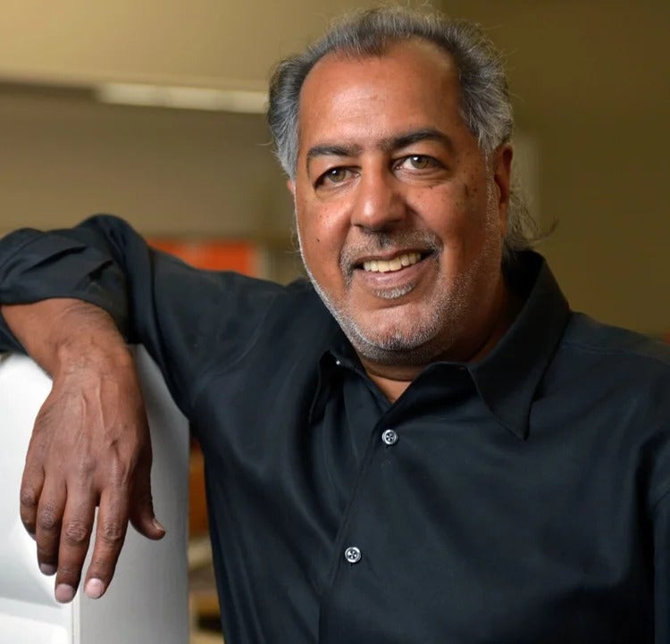 A man smiles at the camera while leaning against something in a lab