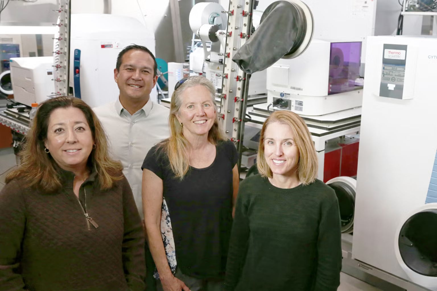 Four people stand in a state-of-the-art facility with industrial equipment
