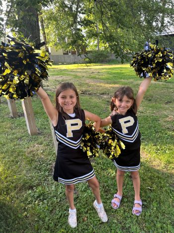 Two young girls in cheerleading gear with pom poms