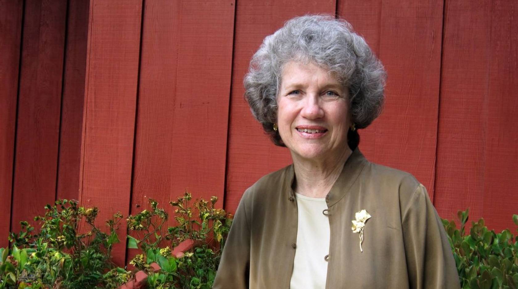 An older woman smiles in a portrait outside