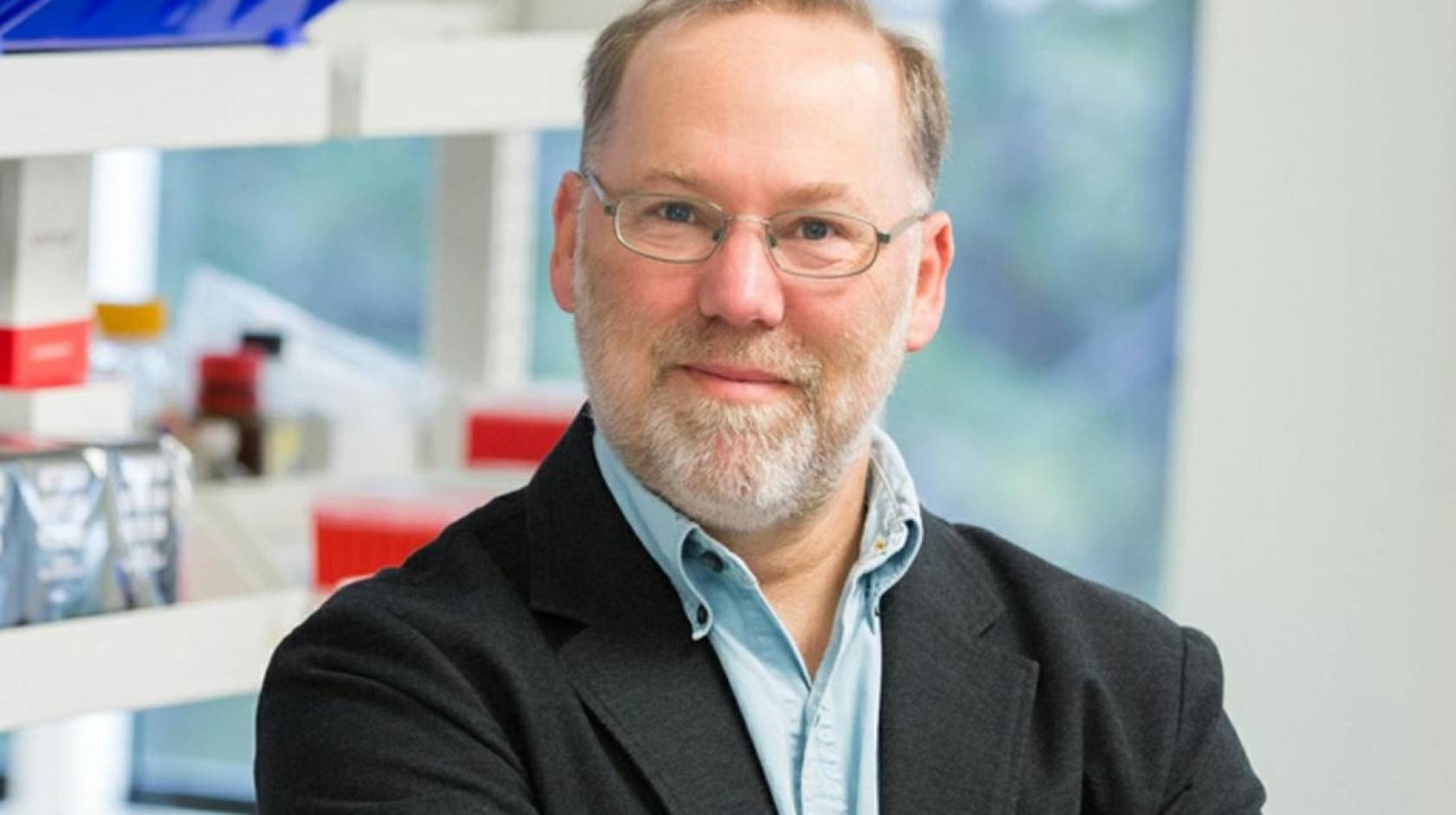 A man with a beard in glasses smiles in a lab