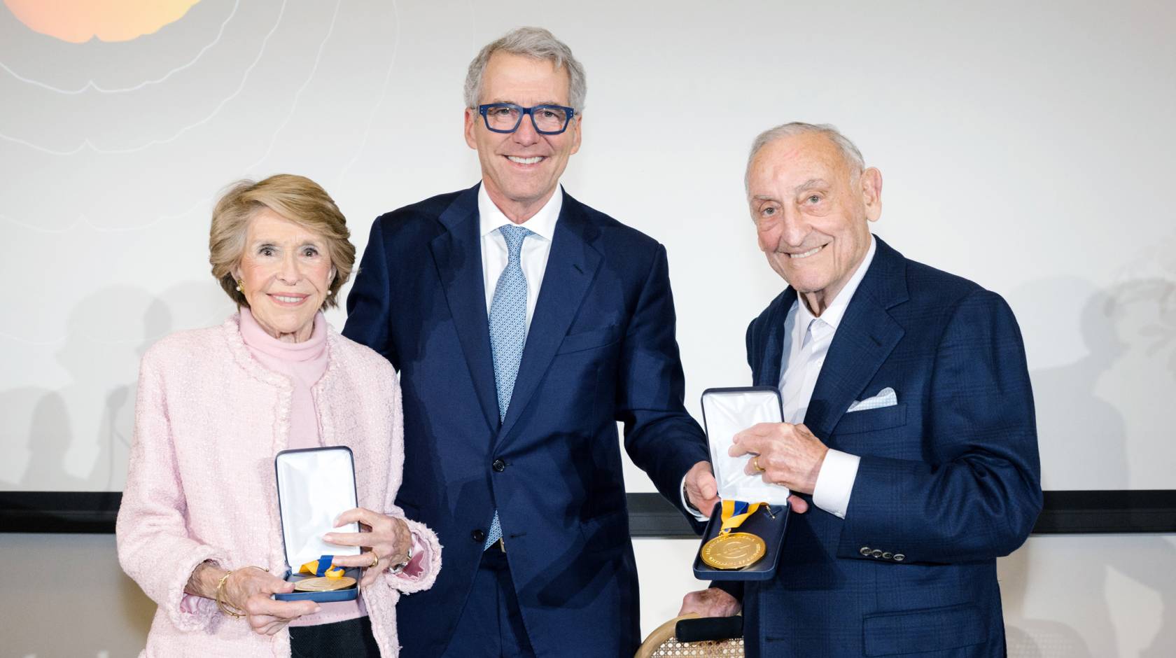 Joan Weill, left, stands next to President Milliken, who is next to Sanford I. Weill, both Weills holding their gold medals 