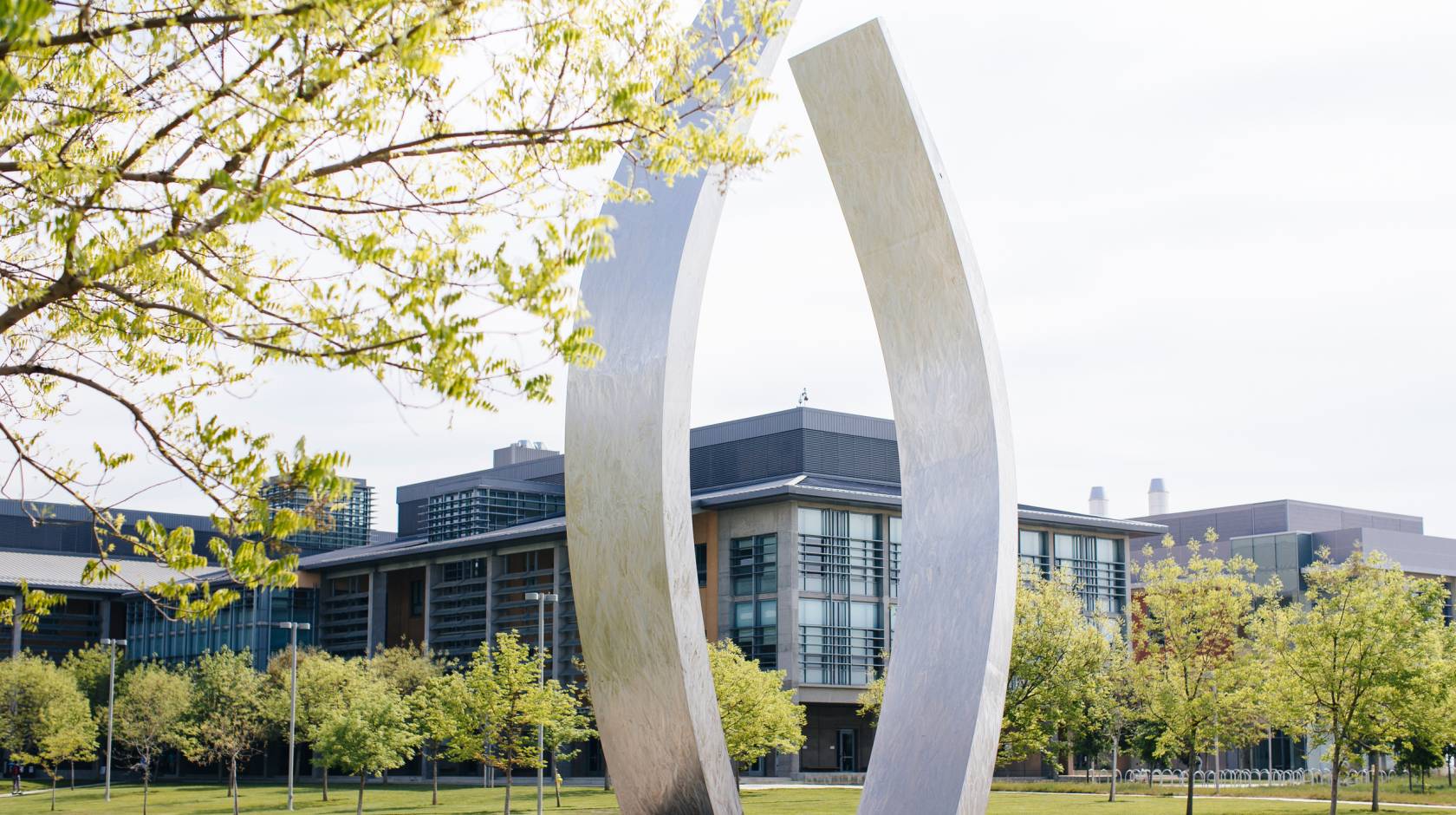 A view of UC Merced's campus with the sculpture, Beginnings, gently curving, vertical stainless steel arms, each about 40 feet high, in the center