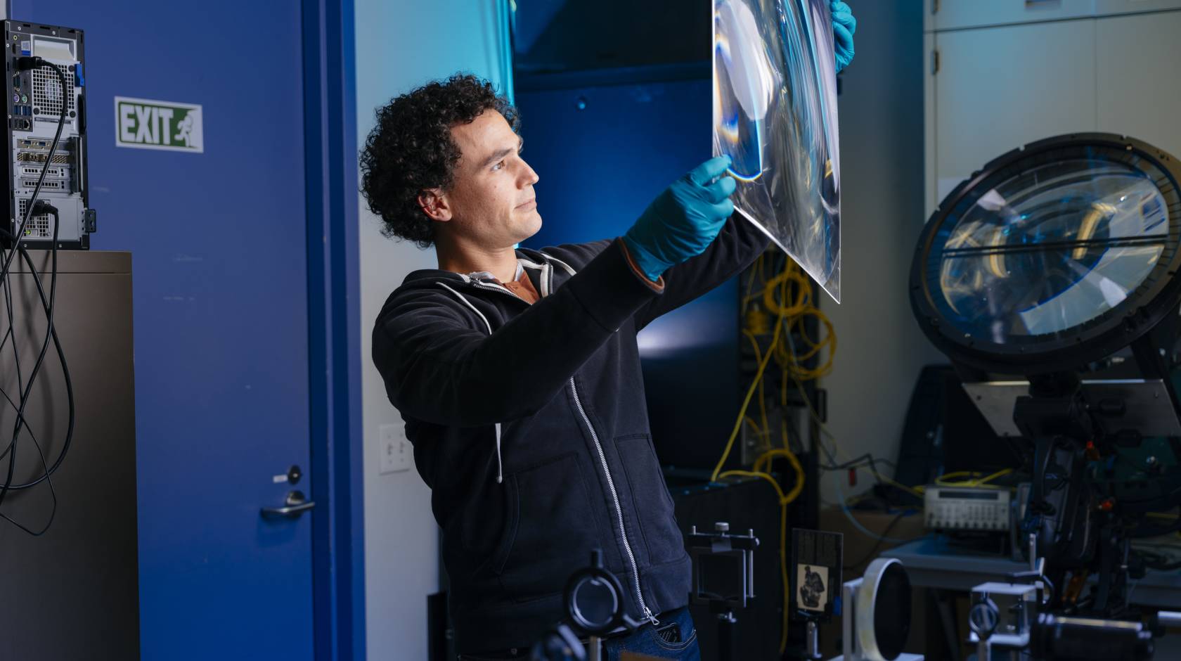 An engineer in a lab holds up a large square of a material to the light