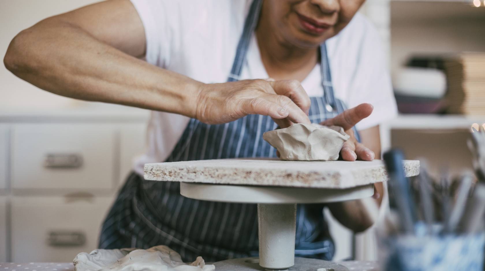 A person wearing an apron working at a ceramics wheel
