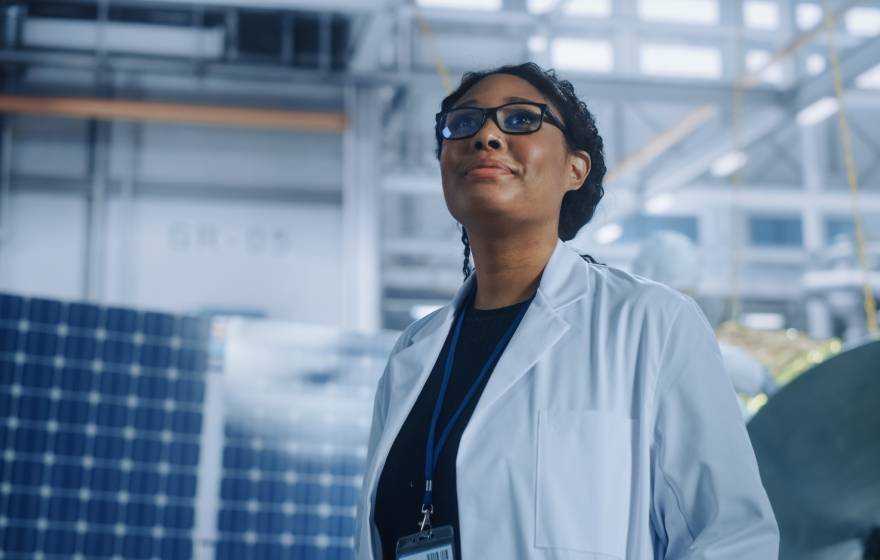 Black woman scientist looking up in a warehouse