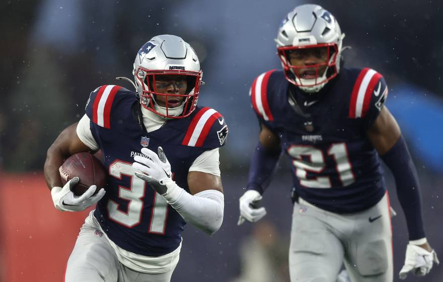Two players for the New England Patriots, one holding the football and running
