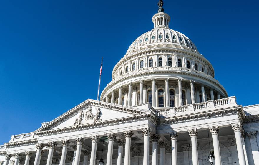 The U.S. Capitol building viewed from an angle against a bright blue sky