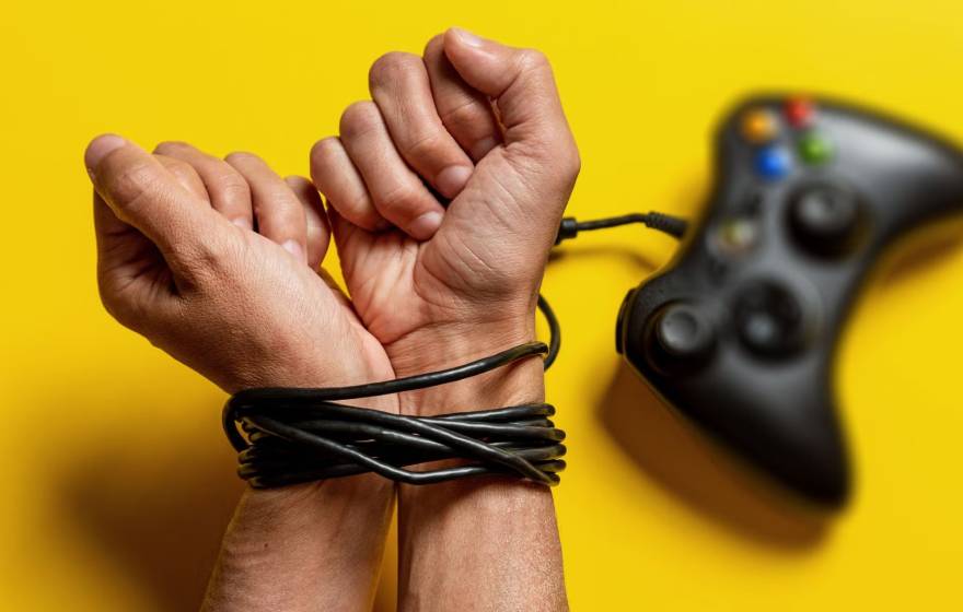 A pair of hands with wrists bound by a gaming console cord