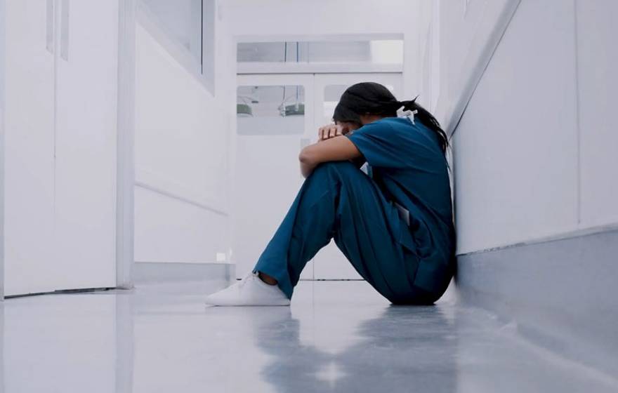 Health care worker sitting on ground frustrated