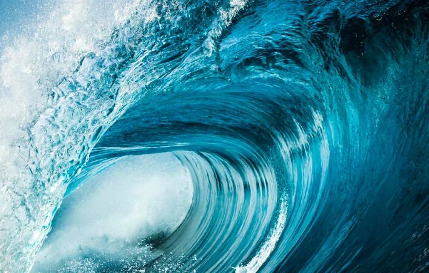 A very blue ocean wave about to crash, seen from the side