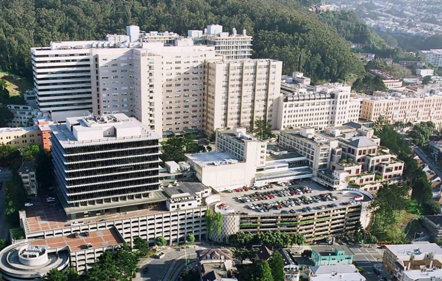 Aerial view of the UCSF Parnassus campus, white buildings at the base of a hill with trees