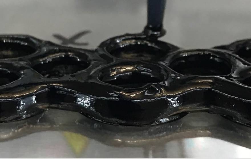 A black, shiny substance molded into a grid of circles
