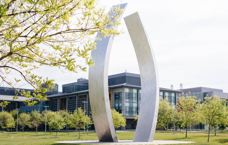 A view of UC Merced's campus with the sculpture, Beginnings, gently curving, vertical stainless steel arms, each about 40 feet high, in the center