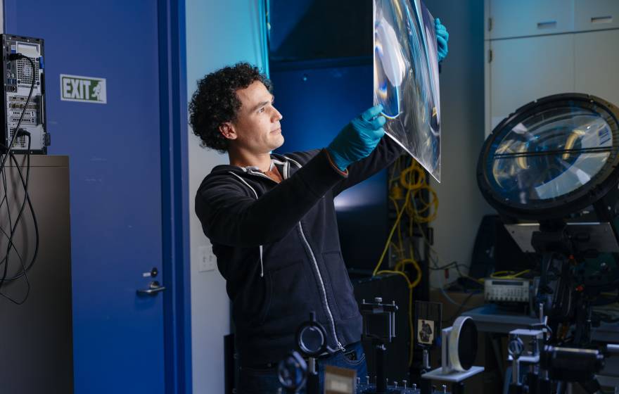 An engineer in a lab holds up a large square of a material to the light