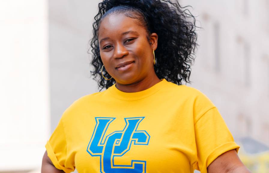 Student on campus with yellow shirt and UC in blue letters