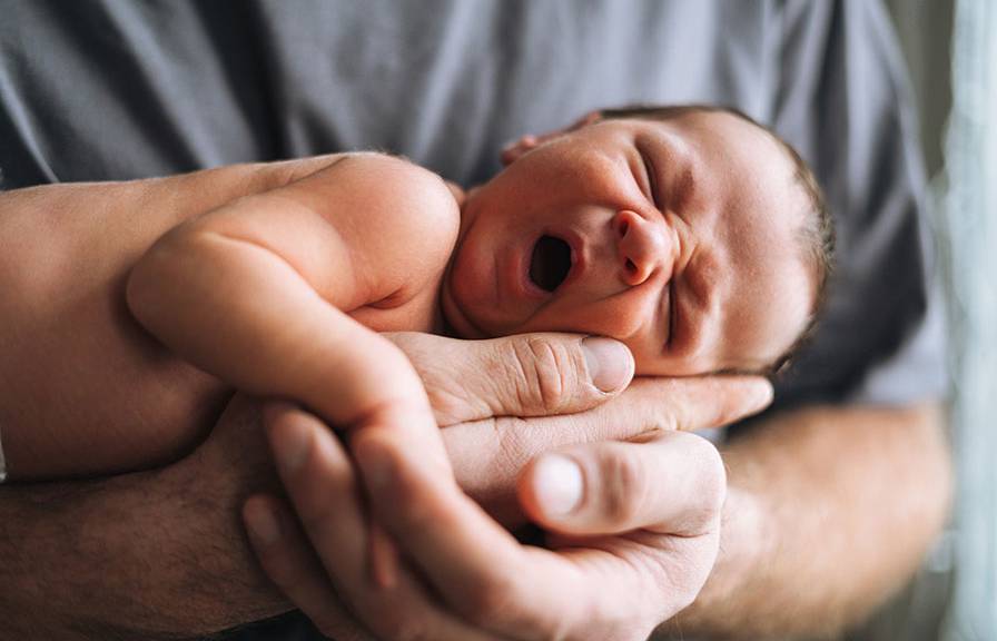A newborn held in a hand