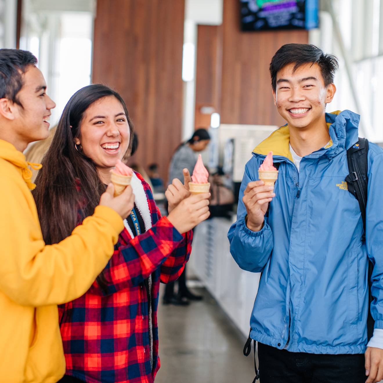 Three smiling students holding ice cream cones